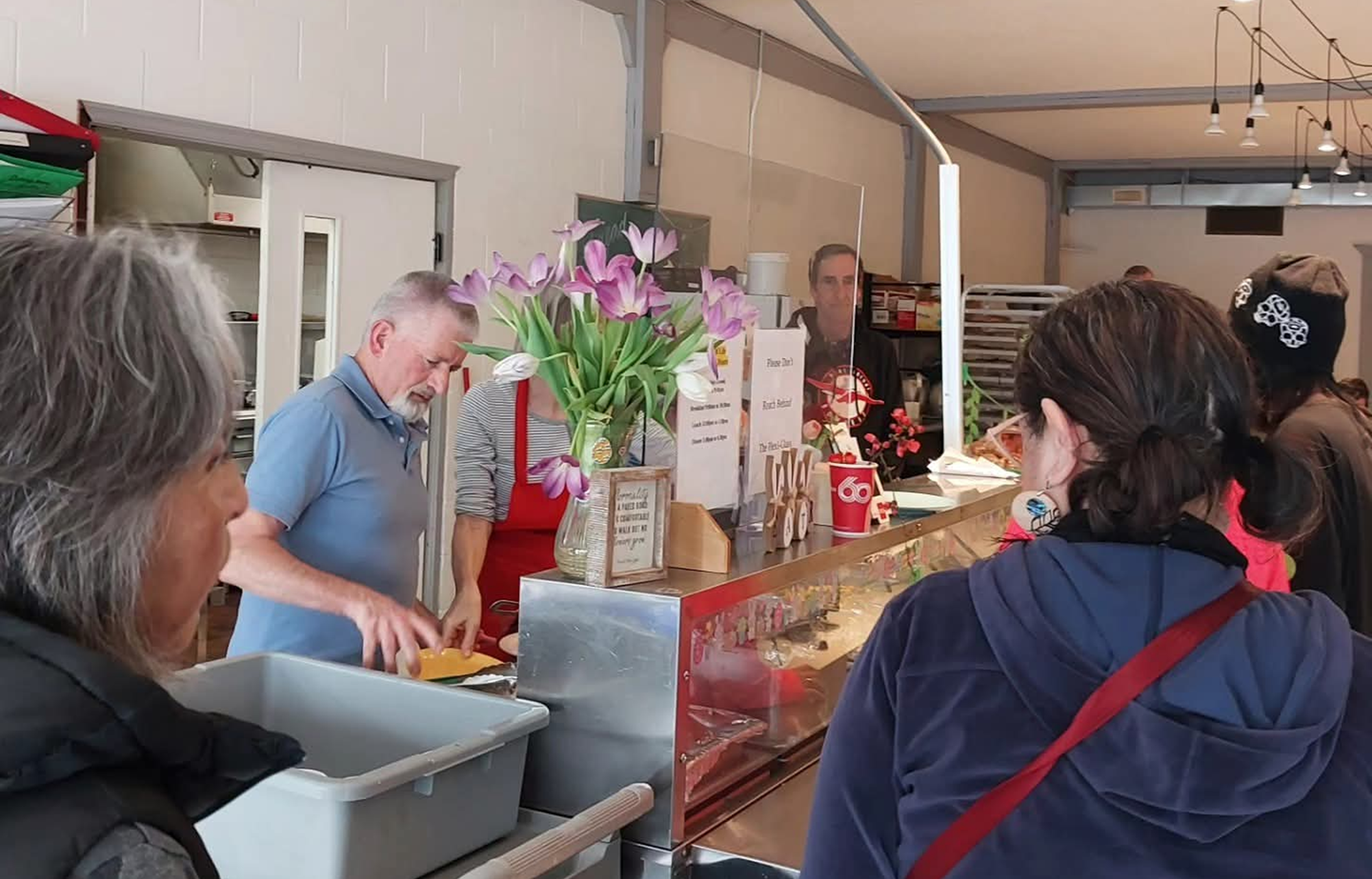 Visitors speaking with staff at the Salvation Army Alberni Valley Ministries, with items and flowers displayed on the counter.