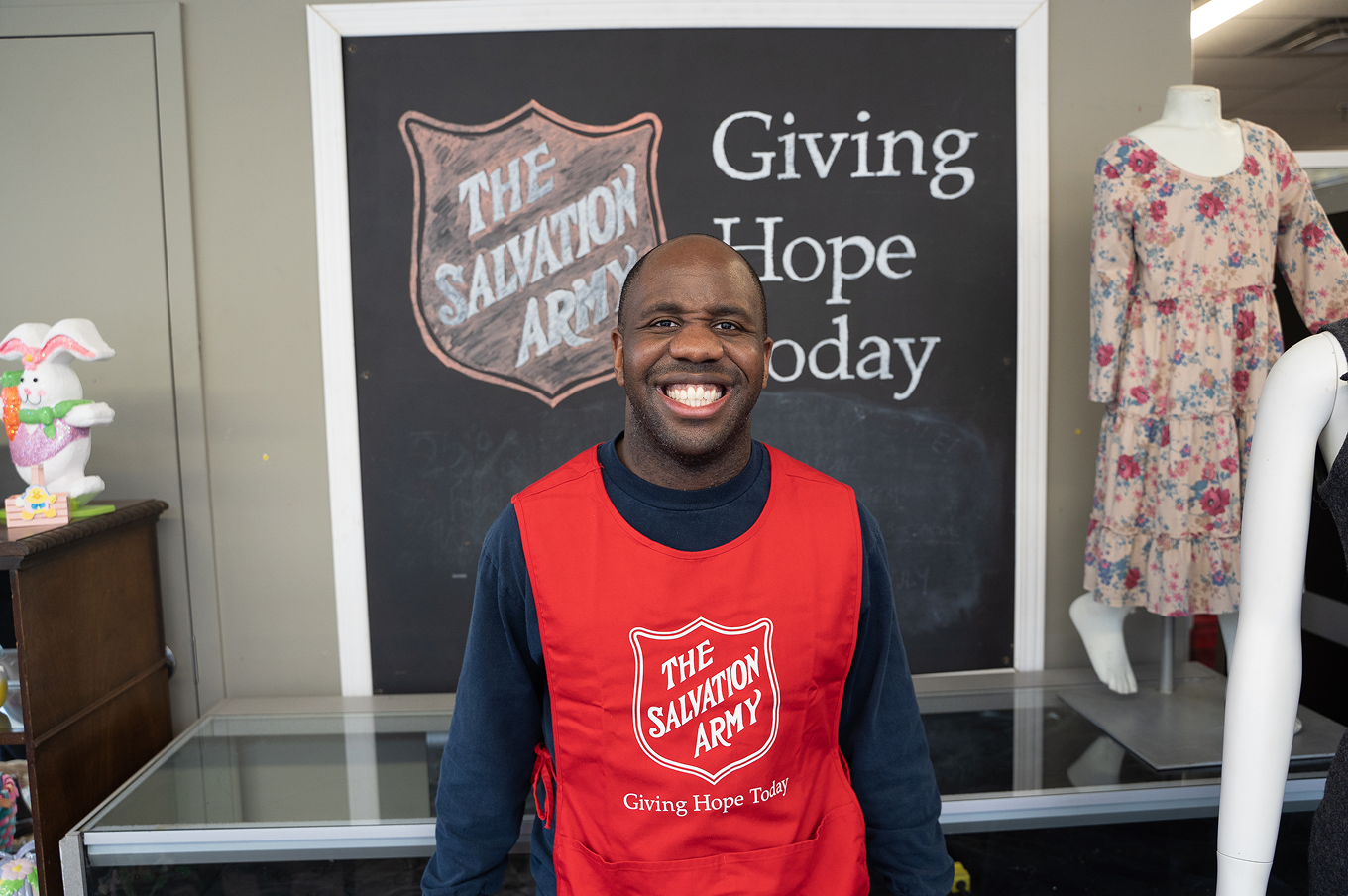 Smiling Salvation Army staff member wearing a red vest.
