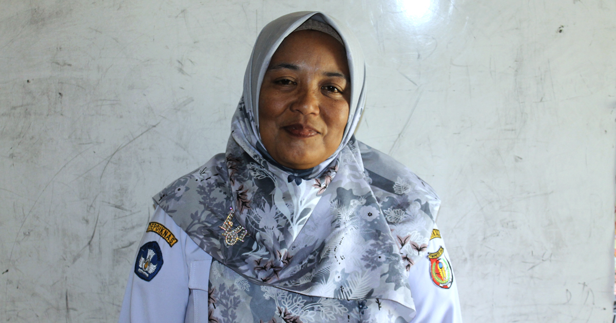 A woman wearing a grey hijab and a white uniform